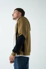 Campera de felpa de diseño color block en tonos marrón y negro, con capucha con cordón ajustable, cierre frontal y bolsillos. Presenta lettering estampado en el pecho.