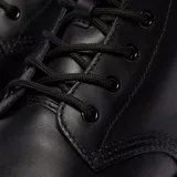 Botas de caña media Dr. Martens modelo Brookline, confeccionadas en cuero negro con acabado ceroso. Presentan cierre de cordones con seis ojales, suela gruesa con costuras amarillas visibles y tirador característico en el talón.