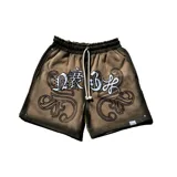 Bermuda de felpa color beige con lavado lateral negro, corte ancho. Presenta un gran estampado serigrafiado frontal con letras blancas de estilo gótico y ornamentos negros, y un aplique bordado sobre la estampa. Cuenta con cordón blanco en la cintura y remaches metálicos cromados.