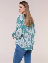 Blusa holgada de gasa texturizada color blanco con estampado de lunares negros, escote en V con botones frontales, mangas 3/4 abullonadas y puños elásticos.