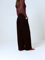 Pantalón de corte sastrero y pierna ancha, color negro, con cintura alta y pinzas frontales.