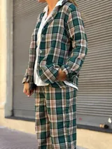 Blazer de corte recto con estampado de cuadros en tonos verdes, beige y negro, con cierre frontal de botones y bolsillos laterales.