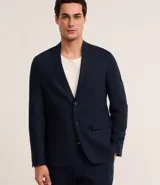 Saco de traje masculino de corte social, confeccionado en mezcla de lino y viscosa. Presenta cierre frontal con dos botones, solapas clásicas, bolsillos laterales con solapa y medio forro interior.