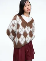 Sweater de tejido de punto con diseño de rombos en tonos marrón y blanco, escote en V y mangas largas.