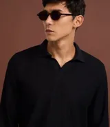 Polo de manga larga color beige claro, confeccionado en tejido texturizado (posiblemente acanalado o waffle). Presenta un cuello polo con escote profundo en V sin botones.