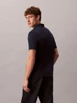 Chomba de manga corta Calvin Klein confeccionada en algodón interlock, con cuello clásico y cierre frontal de botones. Presenta un diseño liso en color azul marino con el logo de la marca sutilmente bordado en el pecho.