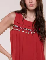 Vestido corto de silueta evasé holgada color marrón, confeccionado en tejido liviano con caída fluida. Cuenta con escote redondo, detalle calado y cinta bordada de estilo étnico con monedas colgantes en el pecho.