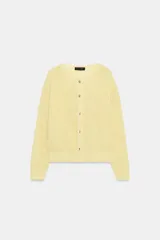 Chaqueta de punto rústico color amarillo claro, con cuello redondo, manga larga y cierre frontal con botones nacarados.