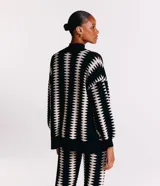 Saco de punto negro con estampado geométrico blanco, manga larga amplia y corte alargado.