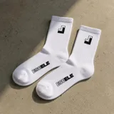 Medias blancas de caña alta con elástico acanalado, con el logo y el nombre de la marca impresos en negro.