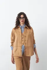 Sobrecamisa de gamuza color marrón, de silueta relajada, con cuello camisero, botones frontales y bolsillos de parche en el pecho.