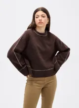 Sweater negro de corte holgado con cuello redondo a la base y detalle de costuras decorativas en contraste a lo largo de las mangas y el cuello.
