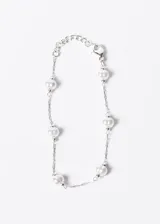 Pulsera plateada de acero quirúrgico con perlas sintéticas blancas.