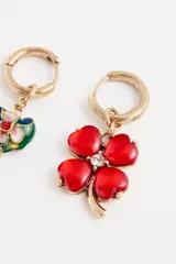 Par de aros tipo argolla con dijes colgantes asimétricos: uno con forma de corazón esmaltado multicolor y otro con forma de trébol de cuatro hojas rojo con centro de cristal.