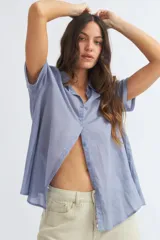 Camisa celeste de manga corta con cuello camisero y abotonadura frontal.