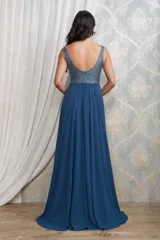 Vestido largo de fiesta color azul petróleo, con cuerpo superior bordado en pedrería y escote en V. Presenta una falda fluida de gasa con una abertura lateral profunda.