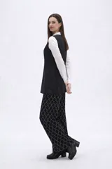 Chaleco largo de corte sastrero en color negro, con escote en V, cierre frontal de botones y bolsillos laterales simulados.