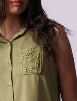 Blusa color crema sin mangas, con cuello camisero, cierre frontal con botones y bolsillo de crochet.