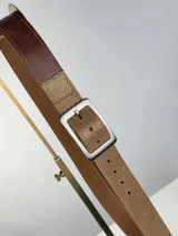 Cinturón de cuero genuino con diseño bicolor, combinando una sección en cuero marrón oscuro y otra en cuero texturizado color dorado. Cuenta con hebilla rectangular metálica de acabado plateado.
