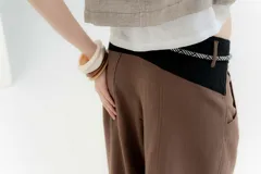 Pantalón blanco de lino y algodón, de tiro medio, con pinzas frontales, pretina ancha en la espalda con cambio de color y vivo en contratono, cortes en la mitad de la pierna de la espalda, cierre frontal con cierre y botón, y bolsillos delanteros.