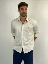 Camisa de manga larga en color beige, confeccionada en tejido de lino con textura sutil. Presenta cuello clásico, cierre frontal con botones y un pequeño logo bordado en contraste en el pecho.