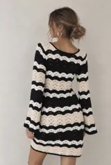 Vestido corto de punto calado con patrón de rayas onduladas en color negro, blanco y beige, de manga larga y escote en V con cordones para atar.