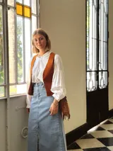 Cartera bandolera de cuero color camel, con forro interno de tela y flecos laterales.