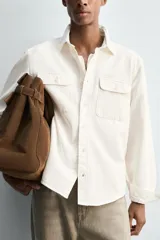 Sobrecamisa de corte regular confeccionada en denim de algodón, con cuello solapa, manga larga con puños abotonados y cierre frontal de botones. Presenta dos bolsillos frontales de plastrón con solapa y bajo con aberturas laterales.