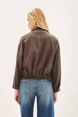 Campera de corte amplio, color marrón, con cierre frontal, bolsillos frontales con solapa y cintura ajustable. Incluye un pin decorativo en la solapa.