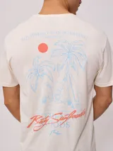 Remera negra de algodón con estampado en la espalda con palmeras, tabla de surf y texto en color blanco y fucsia.