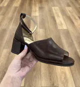 Sandalias de cuero marrón con punta abierta, talón cubierto y tira al tobillo con hebilla. El talón está confeccionado en cuero con textura de reptil.