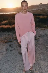 Sweater de punto color rosado con cuello redondo y manga larga, de bajo asimétrico con acabados en rib.