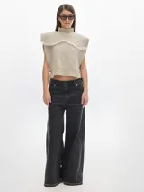 Chaleco marrón de punto con cuello alto y detalle de flecos en el pecho.