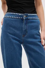 Pantalon de jean negro de corte recto y tiro alto, con detalle de tachas metálicas en la cintura.