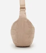 Bolso tipo hobo de diseño media luna con textura arrugada, confeccionado en poliéster color beige. Cuenta con cierre de cremallera y correa ajustable para llevar al hombro o cruzada.