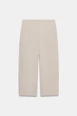 Pantalón de tiro medio con corte tipo ballon, bolsillos delanteros y detalle de pinzas. Cuenta con cierre frontal de cremallera y gancho metálico.