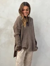 Sweater de punto acanalado color gris, con cuello polo y escote en V. Diseño holgado con mangas largas y aberturas laterales en el dobladillo.