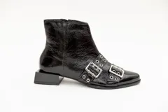 Botas cortas de cuero charol color negro, con aplique de hebillas con ojalillos y cierre lateral. Taco cuadrado bajo.