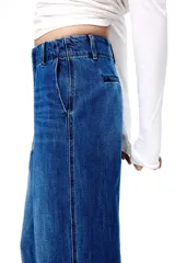 Pantalón de denim de algodón rígido, de corte recto y tiro alto, con pliegues frontales y traseros, bolsillos laterales al bies y cierre oculto.