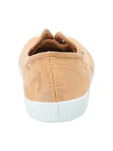Zapatilla tipo sneaker de diseño ligero y fresco, confeccionada en algodón orgánico teñido a mano en tono arcilla. Presenta puntera reforzada de goma blanca, suela de caucho natural y ojales metálicos decorativos.