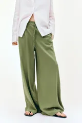 Pantalón de tiro alto con pernera ancha, confeccionado en tejido de lino. Presenta cintura elástica con cordón ajustable, pinzas delanteras, bolsillos laterales y bolsillos de plastrón en la parte posterior.