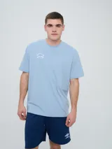 Remera Umbro de manga corta, color celeste, con cuello redondo y el logo de la marca bordado en el pecho.