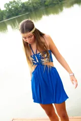 Vestido corto azul con top strapless y detalles de hojas doradas bordadas. Presenta un corte bajo el busto, aberturas laterales en la cintura y breteles finos que se anudan al cuello.