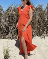 Vestido largo fucsia de lino, con corte recto, breteles anchos con volados y botones frontales. Presenta un tajo lateral.