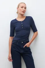 Remera verde de tejido canalé con cuello redondo y media manga. Tiene una abertura frontal con botones.