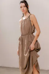 Vestido largo color marrón de crepé plissé, con escote halter adornado con detalles de perlas, silueta fluida y lazo ajustable en la cintura.