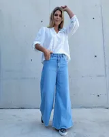 Pantalón de jean color beige, de corte recto y tiro alto, con ruedo deshilachado y cierre frontal con botón y cremallera.