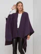 Ruana de tejido suave color morado oscuro, con ribetes de cuero sintético negro en los bordes.