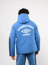 Campera de abrigo Umbro del Club Nacional de Football, con diseño de bloques de color en azul, blanco y rojo. Cuenta con capucha ajustable, cierre frontal y logo de la marca junto al escudo del club en el pecho.