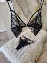 Conjunto de lencería de encaje negro compuesto por un bralette con detalle de aro central y una tanga de doble tira regulable estilo less.